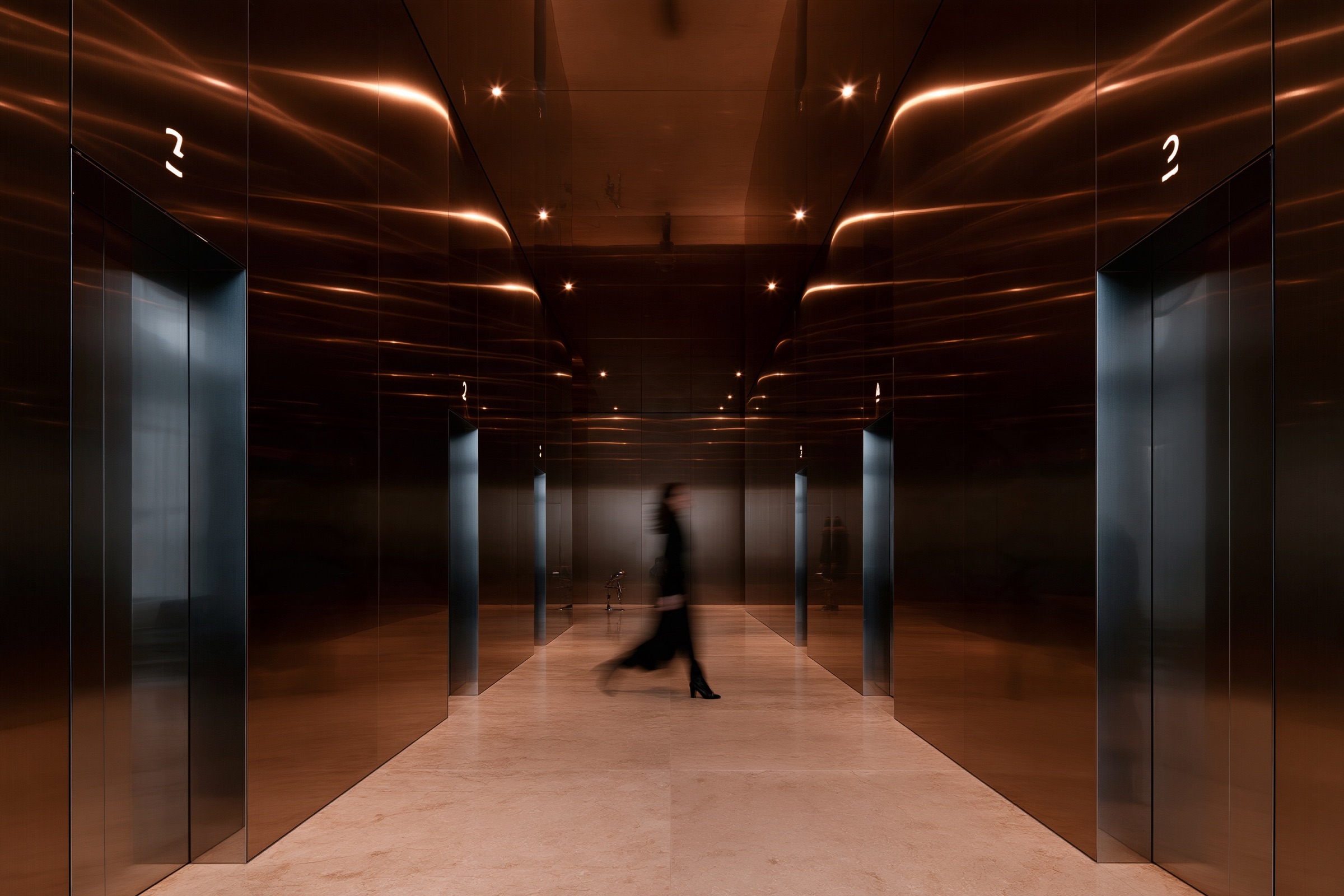 A figure walking through a bronze corridor lit from above
